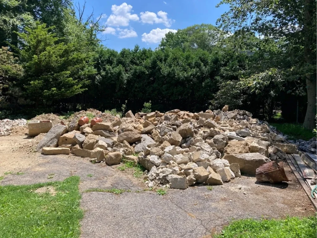 A large pile of concrete and stone debris on a cleared residential property in New Rochelle, NY awaiting removal.